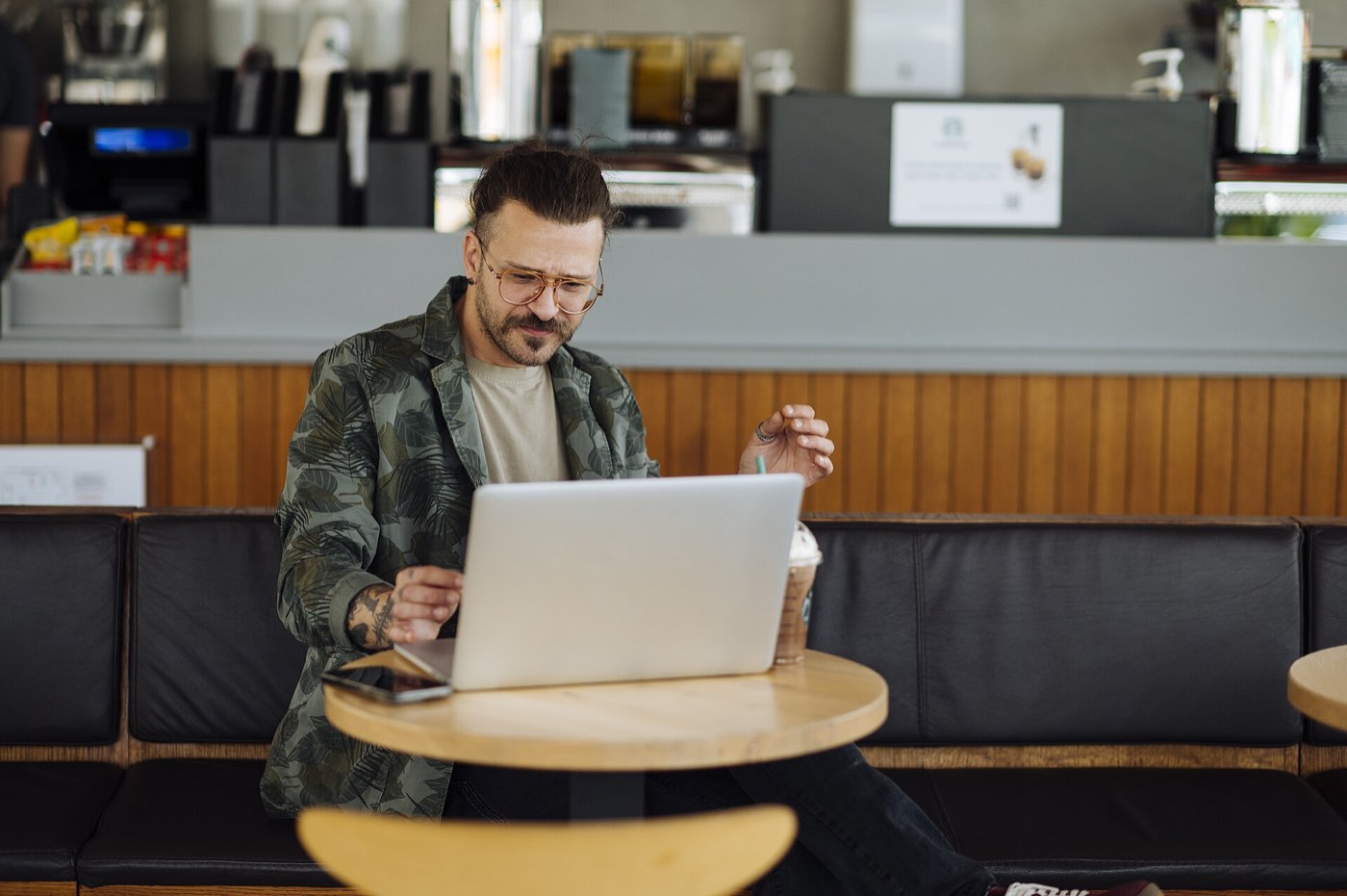 A laptop open on a cafe table beside a coffee