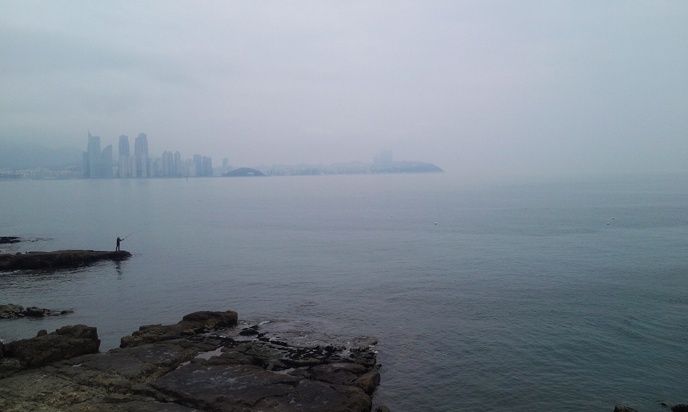 Dongbaekseom and the misty Haeundae skyline seen from the Igidae coastal trail